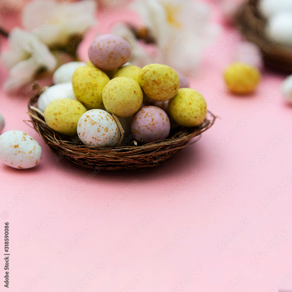 Easter eggs in the nest on pink background. Spring greeting card with copy space.