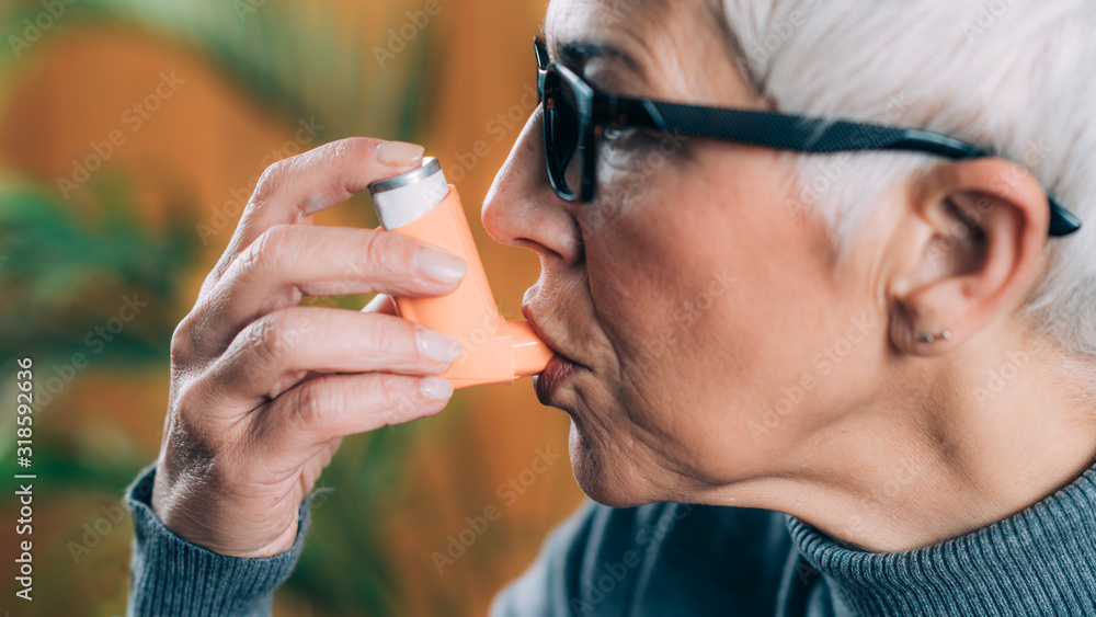 Obraz premium Senior Woman Using Asthma Inhaler with Extension Tube