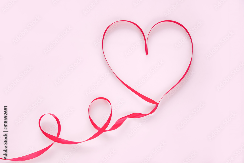 Valentines day concept red ribbon in the shape of a heart on a pink background