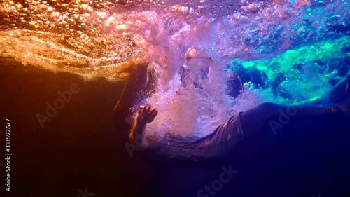 underwater shot in swimming pool, woman is falling inside water, plunging and diving photo