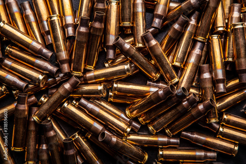 Background from empty cartridges for rifles and carbines. Shiny brass shells scattered on the surface.