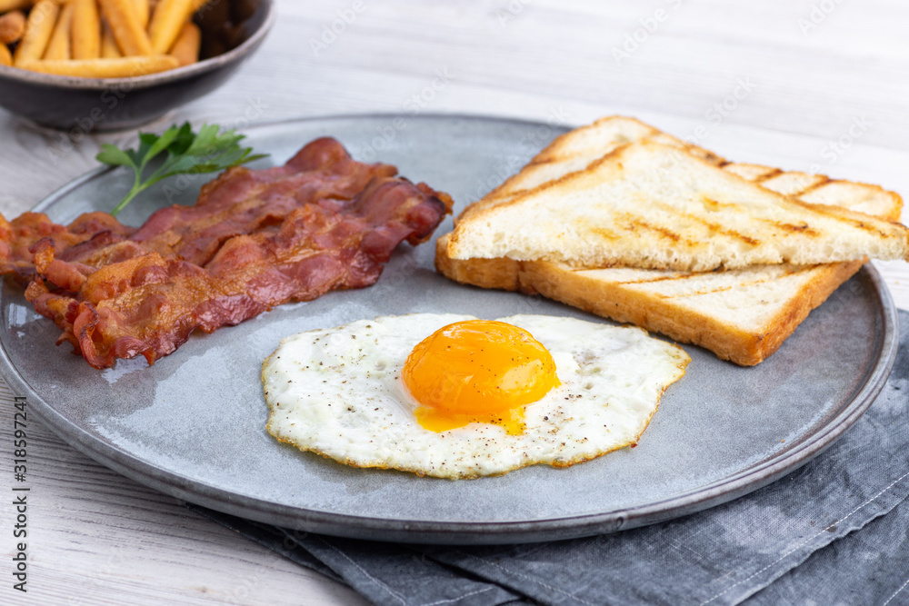 Breakfast - fried bacon pieces and eggs on a plate. Breakfast - fried bacon pieces and eggs on a plate.