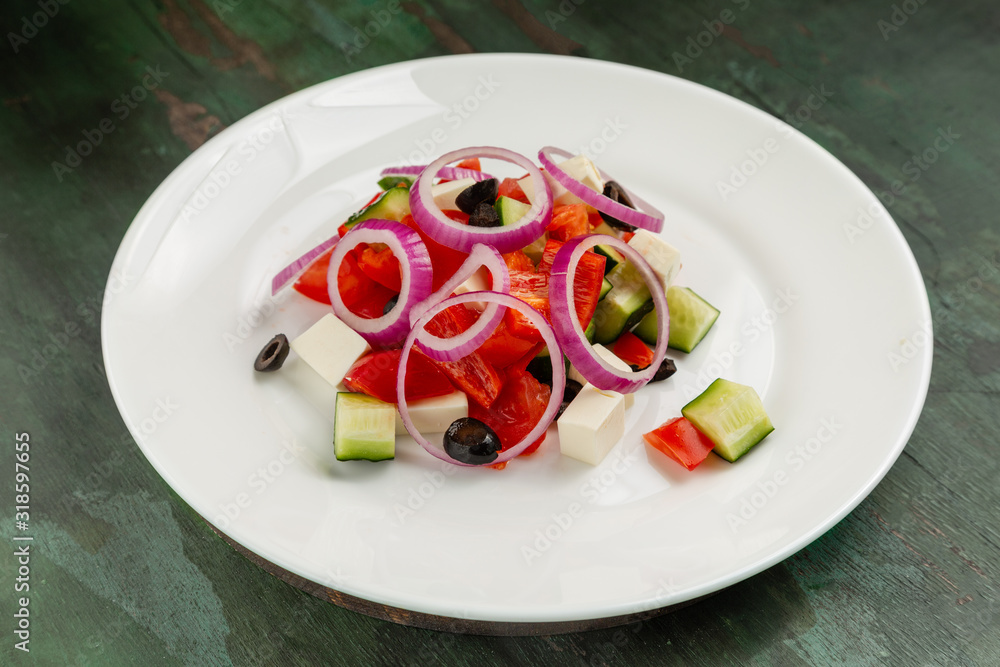 Greek salad in a white plate on a wooden background Greek salad in a white plate on a wooden background