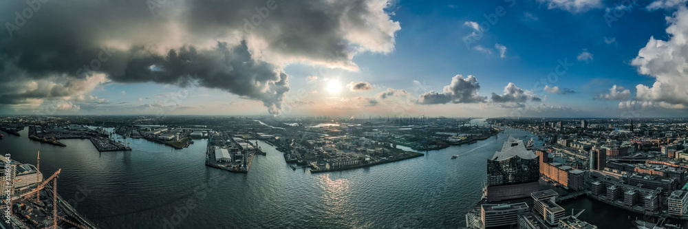 Panoramic aerial drone view of port of Hamburg from Hafencity before sunset with dramatic stormy clouds