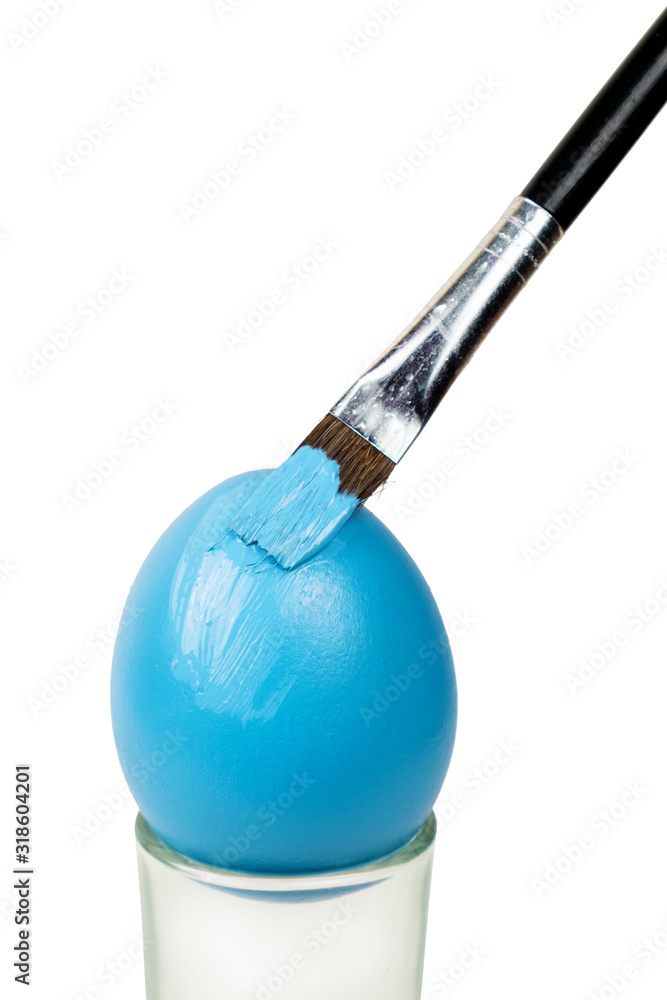 Fototapeta premium Brush painting a Easter egg with blue paint