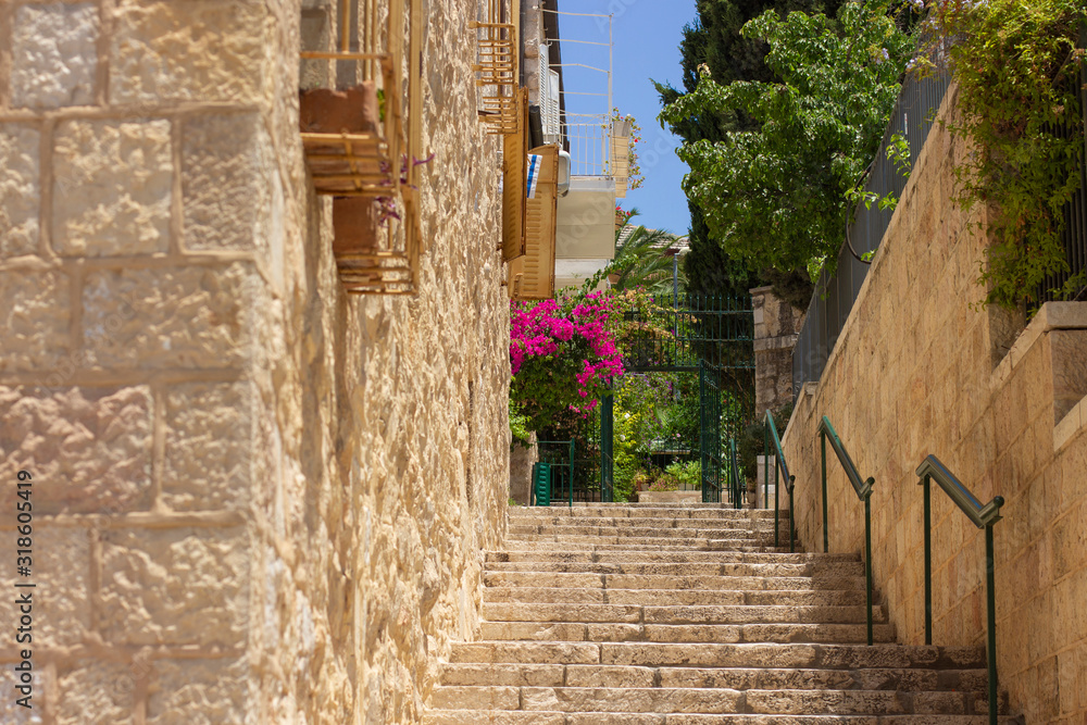 Jerusalem old Israeli city back street stair alley way stone building and blooming flowers and foliage in spring time clear sunny weather day holy land touristic heritage destination