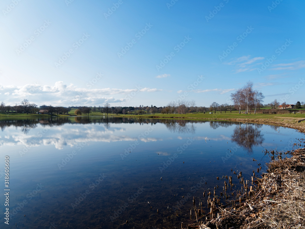 Les eaux calmes du lac de Lapeyrouse dans le Puy-de-Dôme sous un ciel bleu d'hiver