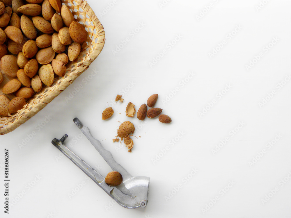 Nutcracker cracks almonds, slices of peeled almonds on a white background Nutcracker cracks almonds, slices of peeled almonds on a white background