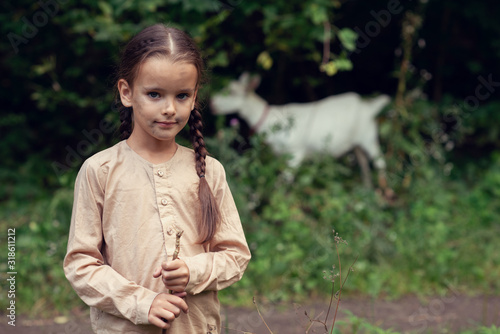 Fotografie Little girl goatherd in forest