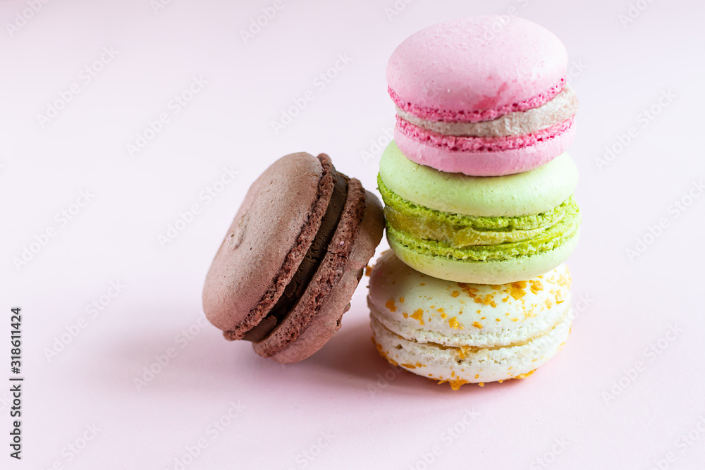 Colorful French macaroons on light pink background close up. Healthy homemade dessert.