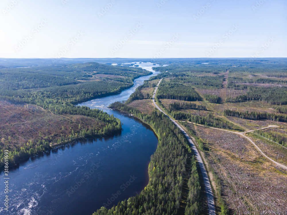 Fototapeta premium View of Kalix river, Kalixalven, Overkalix locality and the seat in Norrbotten county, Sweden, with forest in sunny summer day, aerial drone view