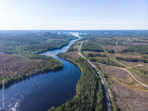 View of Kalix river, Kalixalven, Overkalix locality and the seat in Norrbotten county, Sweden, with forest in sunny summer day, aerial drone view © tsuguliev