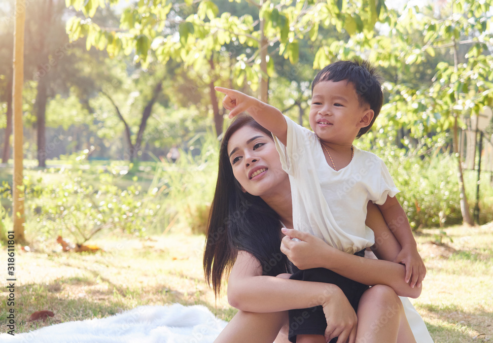 Naklejka premium Young mother with her son spend sunny day in park. Happy family concept.