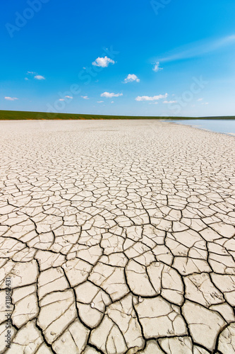 The dry cracked soil on the coast of the salt lake in the bright sunny day. Gruzskoe lake, Rostov-on-Don region, Russia