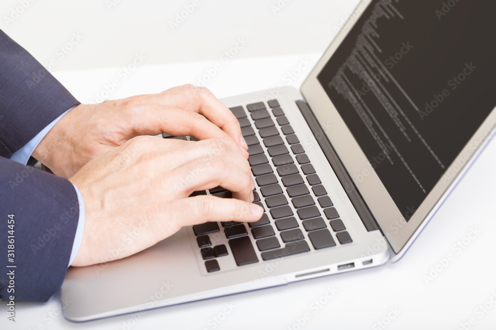 Caucasian male in suit typing something on laptop - studio shot Caucasian male in suit typing something on laptop - studio shot