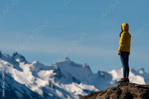 Defocused hiker with yellow jacket admiring views over the Andes. Patagonia, Argentina