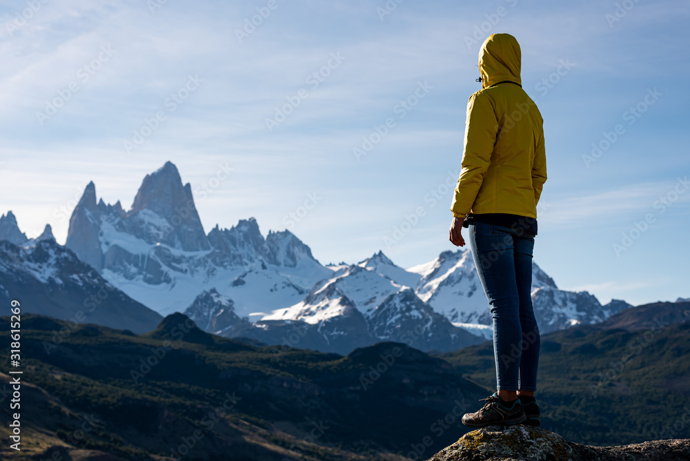 Alone hiker with yellow jacket admiring views over Mount Fitz Roy on the Andes. Patagonia, Argentina