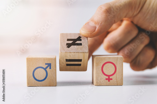 gender equality and discrimination concept - hand putting wooden blocks with symbols photo