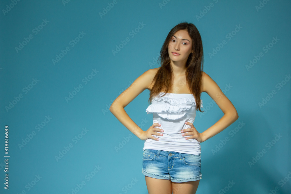 beautiful cheerful teen girl in jean shorts and white top over blue ...