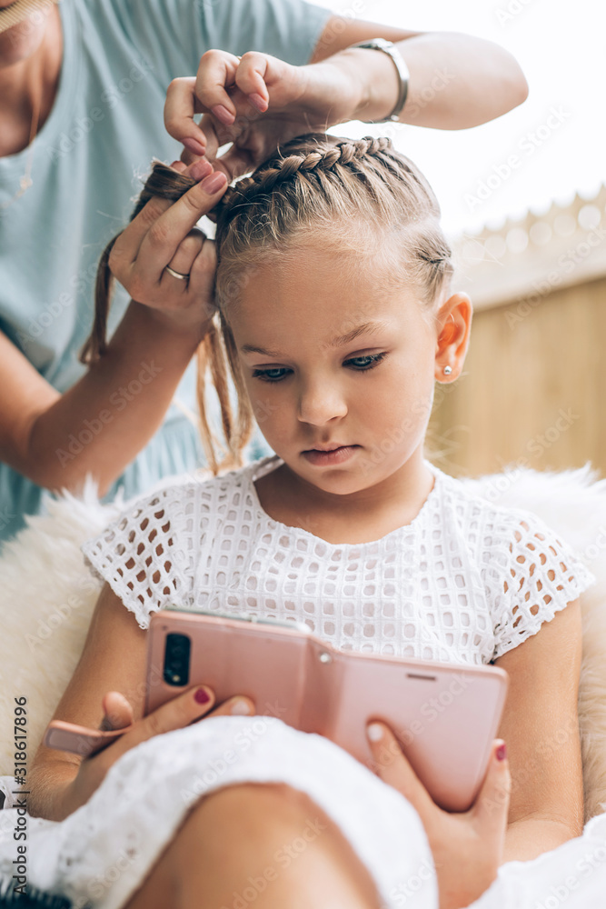 Naklejka premium Mother do hair braid to her daughter, close up photo