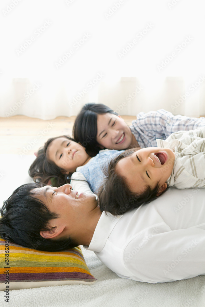 Smiling parents with two children laying on floor at home Smiling parents with two children laying on floor at home