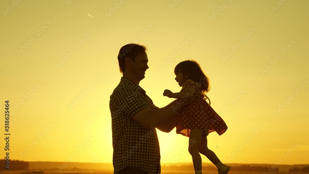 father and little daughter whirl in dance at sunset. concept of happy childhood. Dad is dancing with child in her arms. happy child plays with his father at sunset. concept of happy family