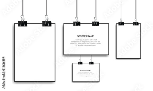 Blank white poster hanging with binder clips.