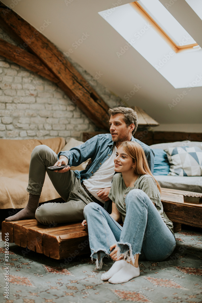 © BGStock72 - Smiling lovely young couple relaxing and watching TV at home © BGStock72 - Smiling lovely young couple relaxing and watching TV at home