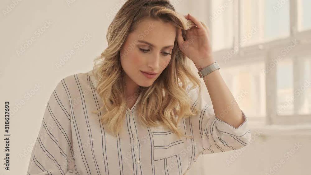 A beautiful focused calm young woman is using her laptop while sitting in white office A beautiful focused calm young woman is using her laptop while sitting in white office