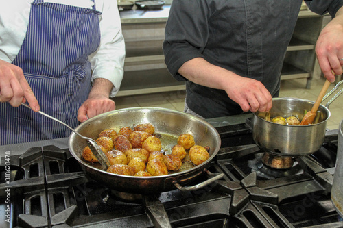 Chefs cook potatoes in a pot in a restaurant kitchen