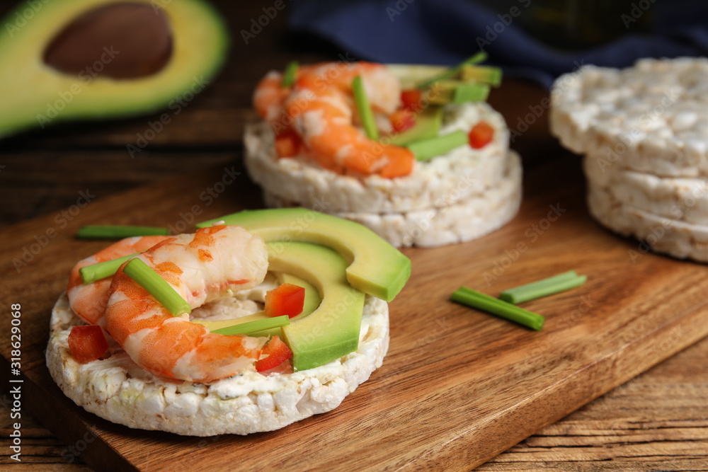 Puffed rice cakes with shrimps and avocado on wooden board, closeup Puffed rice cakes with shrimps and avocado on wooden board, closeup