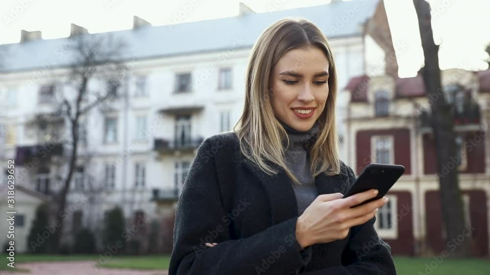 Attractive woman typing Messages on her Smartphone while having a standing in the Street. Having fun and enjoying time outdoor. Pretty brunette with Smartphone in front of Camera. Beautiful girl Attractive woman typing Messages on her Smartphone while having a standing in the Street. Having fun and enjoying time outdoor. Pretty brunette with Smartphone in front of Camera. Beautiful girl