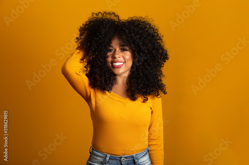Young afro-american woman with curly hair looking at camera and smiling. Cute afro girl with curly hair smiling looking at camera.