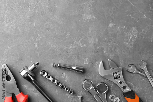 Auto mechanic's tools on grey stone table, flat lay. Space for text photo