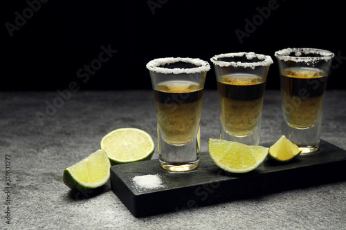 Mexican Tequila shots, lime slices and salt on grey table