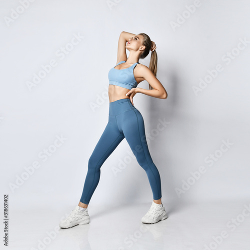 Beautiful sports woman in sport wear after working out sports exercises looking up on grey