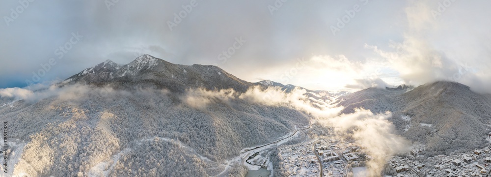 Naklejka premium Aerial view of Krasnaya Polyana, mountains covered by snow and beautuful clouds. Russia.