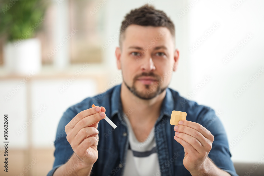 Man with nicotine patch and cigarette at home, focus on hands Man with nicotine patch and cigarette at home, focus on hands
