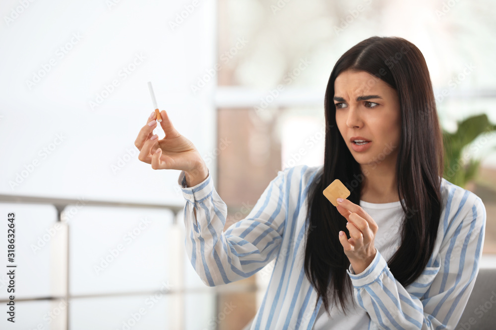 Emotional young woman with nicotine patch and cigarette at home Emotional young woman with nicotine patch and cigarette at home