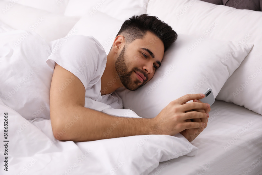 Young man addicted to smartphone in bed at home Young man addicted to smartphone in bed at home