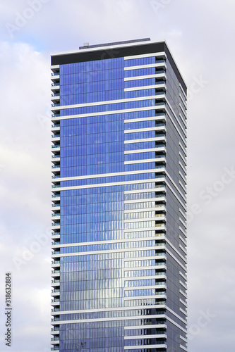 Abstract architecture. Modern building skyscraper on blue cloudy sky background. The texture of the windows of the building. 