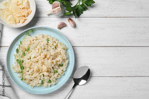 Delicious risotto with cheese on white wooden table, flat lay. Space for text