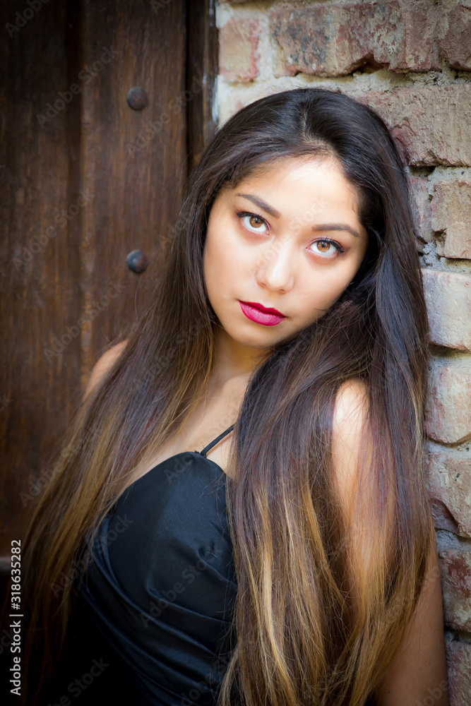 Fototapeta premium Young beautiful woman next to textured stone building.