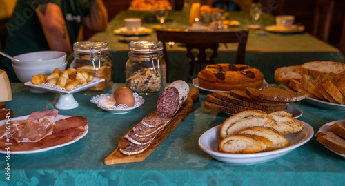 Breakfast on table in small italian farmhouse. Traditional Italian ciabatta bread with herbs, salami, eggs and hamon.