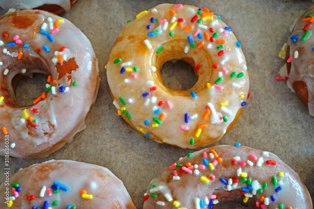 Fresh donuts with white icing and colorful sprinkles