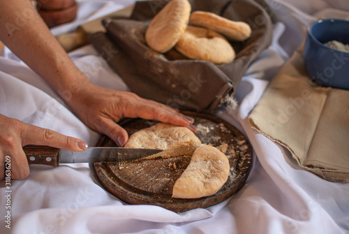 manos de mujer cortando con cuchillo pan casero recién horneado