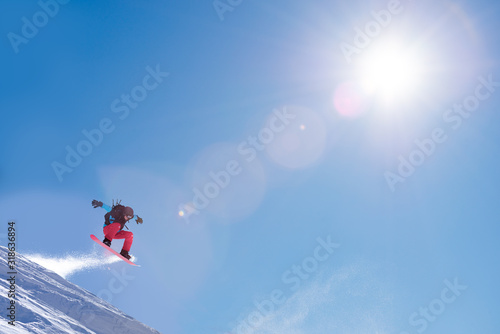 Snowboarder Jumping High on Snowboard in Mountains at Sunny Day. Snowboarding and Winter Sports