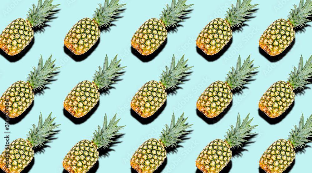 Creative pattern of fruit whole pineapples with shadows on a soft blue summer background. Clipping Path. Creative pattern of fruit whole pineapples with shadows on a soft blue summer background. Clipping Path.