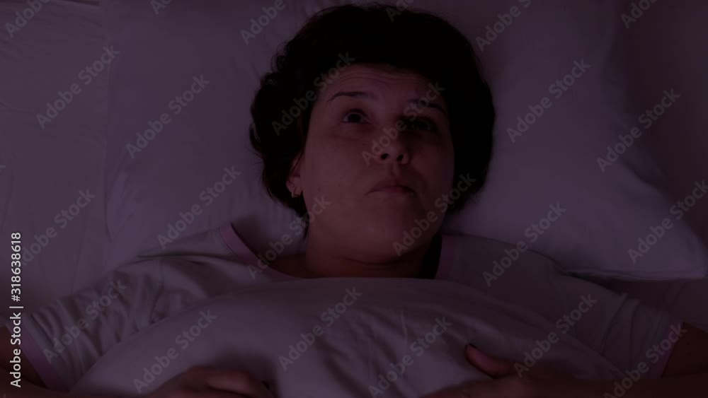 Top view. Woman can't sleep from noise and covers at night Top view. Woman can't sleep from noise and covers at night