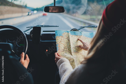 Happy couple traveling by authentic car in Europe, hipster girl holding touristic map planning route in mountains, lifestyle roadtrip travel concept